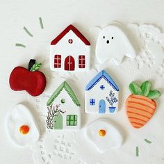 some little houses and carrots are on a white tablecloth with green dots around them