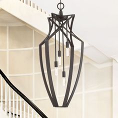 a chandelier hanging from the ceiling in a room with white walls and stairs