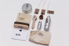 the contents of a personal grooming kit laid out on a white surface with scissors, shaving brush, and other items