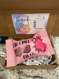 a pink candy bar sitting inside of a box on top of a counter next to other items