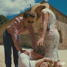 a man is being assisted by a woman on the beach in front of an old building