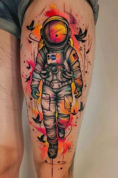 an astronaut tattoo is shown on the leg, with colorful paint splatters around it