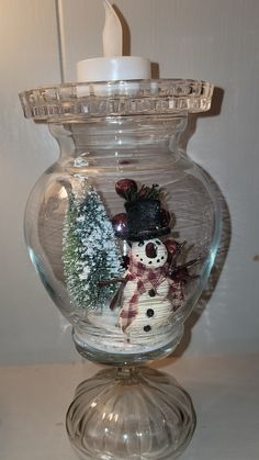 a glass jar with a snowman and trees inside