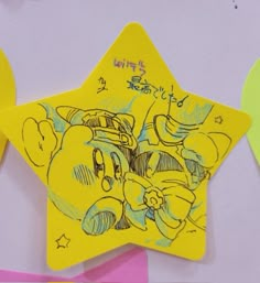 a yellow star shaped paper with cartoon characters drawn on it and some other decorations in the background