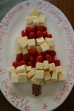 a christmas tree made out of cheese and strawberries is displayed on a white plate