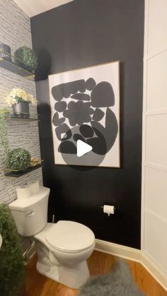 a white toilet sitting next to a sink in a bathroom under a painting on the wall