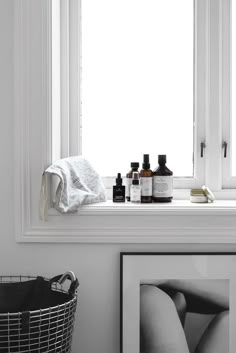 a window sill filled with bottles and soaps next to a framed photograph on the wall