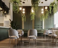 an empty restaurant with chairs and plants hanging from the ceiling, along with wooden flooring