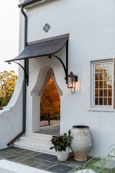 an entrance to a white building with a potted plant