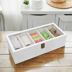 a white box filled with lots of different items on top of a wooden table next to a cup