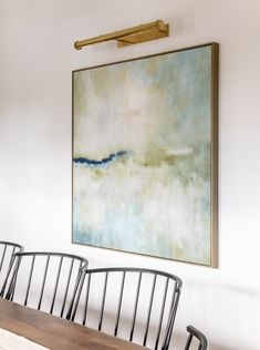 a painting hanging on the wall above a dining room table with four chairs and a bench