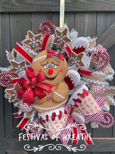 a christmas wreath hanging on the side of a wooden door with red and white decorations