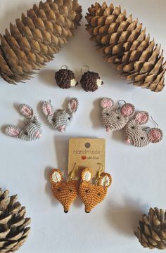 crocheted animals and pine cones are arranged on a white surface with a card