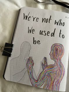 an open notebook with a drawing of two people holding hands and the words we're not who we used to be