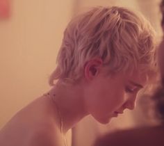 a woman with blonde hair is looking at herself in the mirror while wearing a necklace