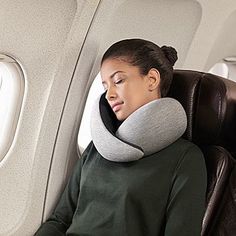 a woman sleeping on an airplane with her head resting on the pillow in front of her