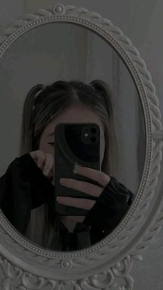 a woman taking a selfie in front of a mirror with her cell phone up to her face