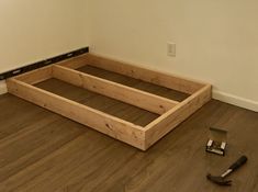 a wooden bed frame with tools laying on the floor