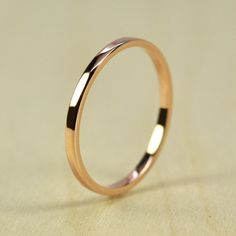 a gold wedding ring sitting on top of a white surface with the light shining through it