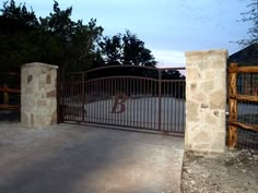 an iron gate is open to reveal a driveway