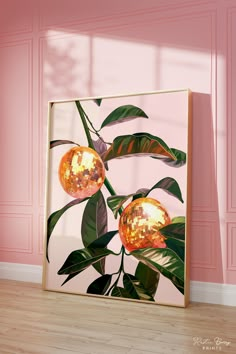 an art piece with two oranges on it in front of a pink wall and wooden floor