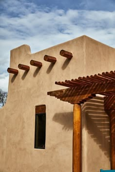 an adobe building with wooden pergols on the side and blue sky in the background