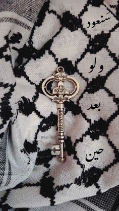 an old key is sitting on top of a scarf with arabic writing in the background