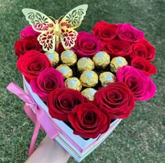 a heart shaped box filled with red roses and chocolates in the shape of a butterfly