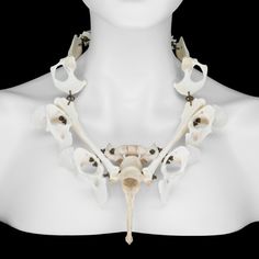 a white mannequin wearing a necklace with skulls and bones attached to the neck