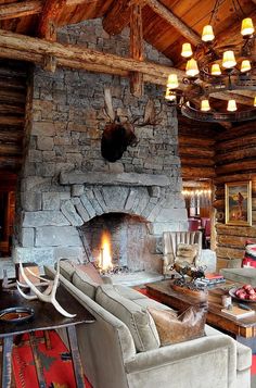 the living room is decorated in rustic style with stone fireplace and deer head mounted on the wall