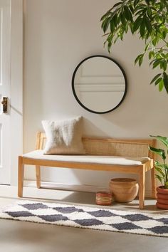 a wooden bench sitting next to a potted plant on top of a white rug