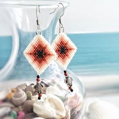 a pair of beaded earrings with seashells and shells in the foreground