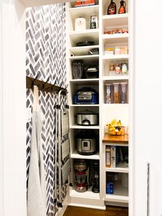 an organized pantry with white shelves and black and white wallpaper, along with various kitchen items