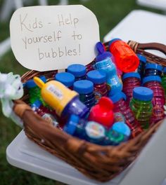 a basket filled with lots of different types of bottles next to a sign that says kids help yourself to bubbles