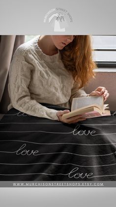 a woman is reading a book while sitting on a couch with the words love over her face