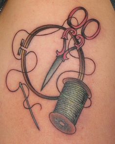 a tattoo on the back of a woman's shoulder with scissors, thread and spools