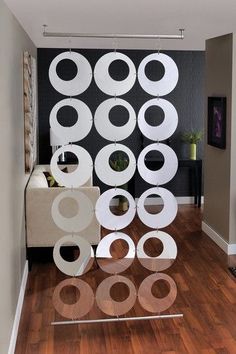 a living room filled with furniture and lots of white circles on the wall next to a wooden floor