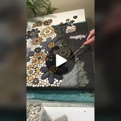 a person is cutting into a large piece of art with rocks and stones on it