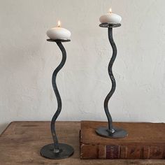 two candles are sitting next to each other on top of a wooden table with an old book