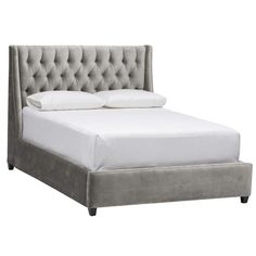 an upholstered bed with white linens and buttons on the headboard is shown