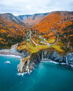 an aerial view of the coast and mountains in autumn time, looking down on a road running through it