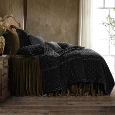 the bed is made with black comforters and pillows on it, along with a potted plant