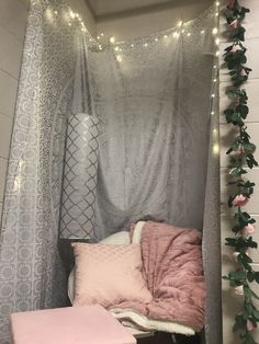 a bed with pink pillows and lights hanging from the ceiling in a room that has white brick walls