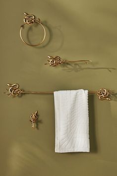 a towel hanging on the wall next to two gold rings and a ring with leaves