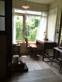 an empty room with a desk, chair and window overlooking the woods in front of it