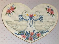 a cross stitch heart with two doves on it