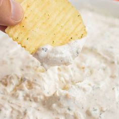 a person dipping a cracker into a bowl of dip