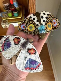 three butterflies are sitting on someone's hand in front of some thread spools