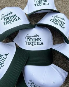 six hats with the words drink tequila written in green and white caps are laid on top of each other