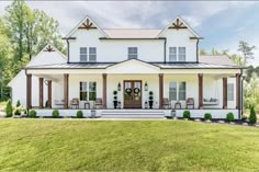 the front view of a white house with porches and columns on each side, surrounded by green grass